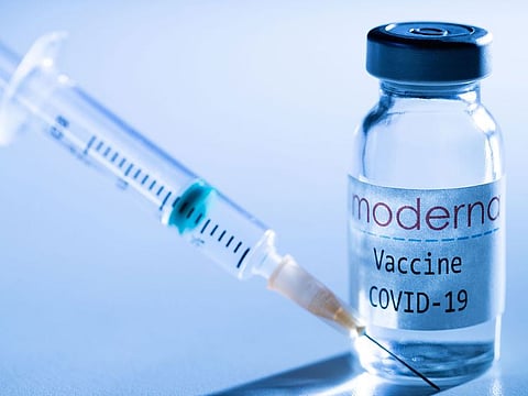 This illustration picture taken in a studio in Paris on November 16, 2020, shows a syringe and a vial with the logo of US biotech firm Moderna.  