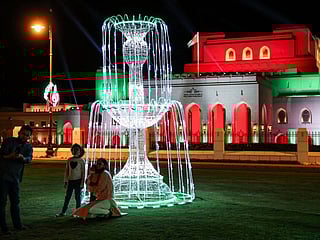 Indian residents of Oman pose for a picture on the lawn before the Royal Opera House Muscat in Oman's capital, lit up with the national colours on the occasion of the Omani national day.