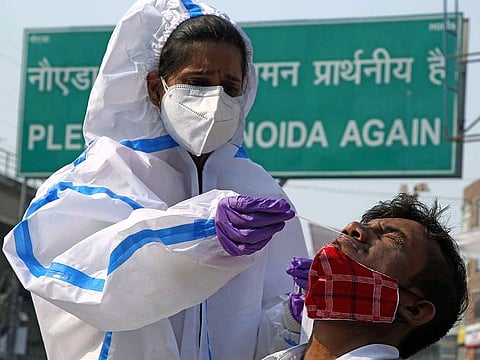 Medical staff collect swab samples from people who are travelling by metro from Delhi to Noida at Botanical Garden Metro in Noida on Thursday. 