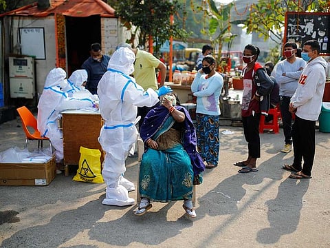 A healthcare worker wearing personal protective equipment (PPE) collects a swab sample from a woman amidst the spread of the coronavirus disease (COVID-19), at Delhi-Uttar Pradesh border, in Noida, India, November 19, 2020. 