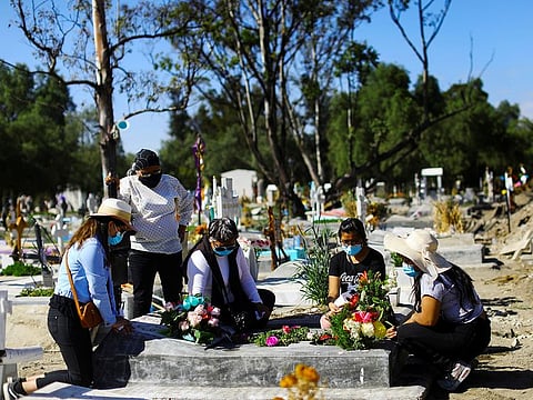 Relatives visit the grave of Natalia, who died on August of the coronavirus disease (COVID-19) at the age of 86, as Mexico surpasses 100,000 deaths from the virus, in Mexico City, Mexico, November 16, 2020. 