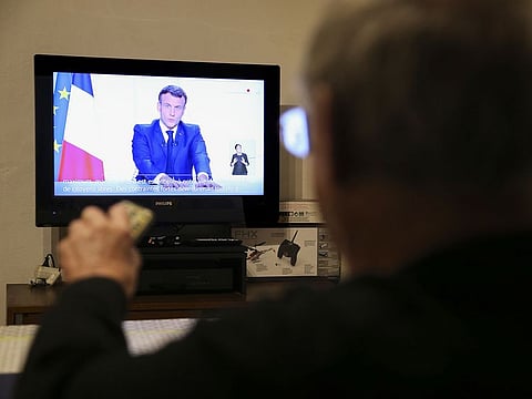 A man watches French President Emmanuel Macron on television on November 24, 2020 in Cognocoli-Monticchi on the French Mediterranean island of Corsica, as he speaks during a televised address to the Nation on the Covid-19 pandemic and lockdown measures.