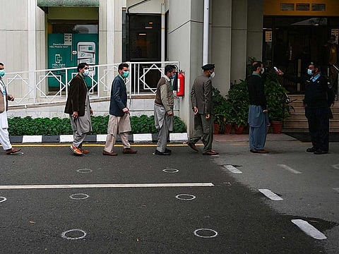 A police officer (R) checks the body temperature of people entering the Supreme Court building in Islamabad on November 25, 2020. 
