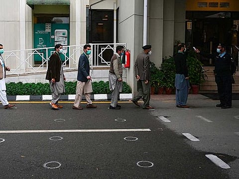 A police officer (R) checks the body temperature of people entering the Supreme Court building in Islamabad on November 25, 2020. 
