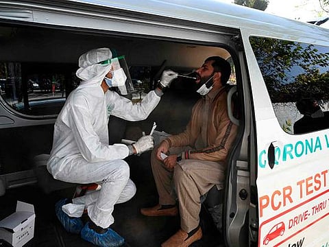 A health official collects a swab sample from a man to test for the COVID-19 coronavirus inside a van along the roadside in Islamabad. According to the National Command & Operation Centre (NCOC) after 59,745 tests conducted in past 24 hours, the COVID-19 positivity rate also dropped from 6.65 per cent to 6.33 per cent.