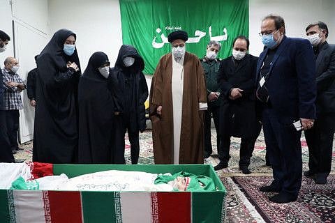 Ebrahim Raisi, head of Iran's judiciary, and family members of Iranian nuclear scientist Mohsen Fakhrizadeh, stand next to his body in Tehran, Iran November 28, 2020. 