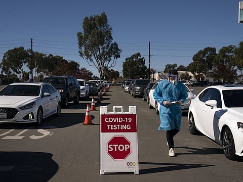 Student nurse Ryan Eachus collects forms as cars line up for COVID-19 testing at a testing site set up the OC Fairgrounds in Costa Mesa, California.