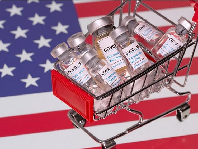 A small shopping basket filled with vials labeled "COVID-19 - Coronavirus Vaccine" is placed on a U.S. flag in this illustration taken November 29, 2020. Picture taken November 29, 2020. 