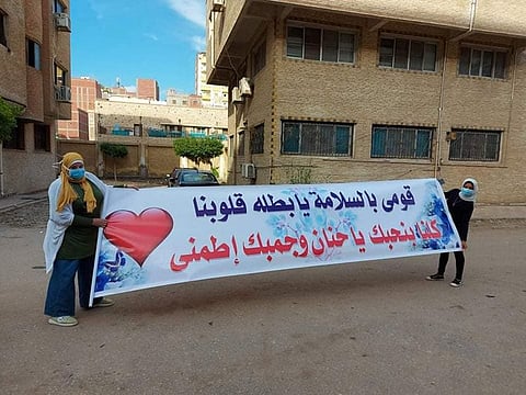 Colleagues of an Egyptian pharmacist infected with COVID-19 display a sign in a show of support for her in a hospital where she is staying.