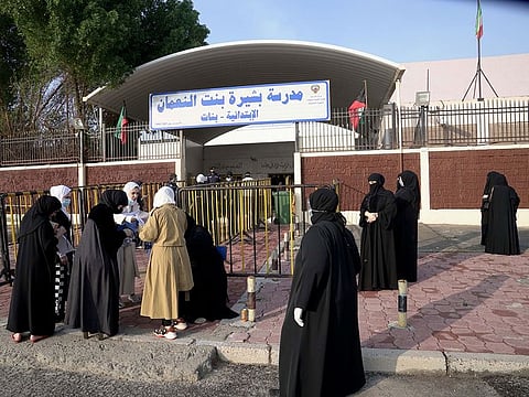 Kuwaiti women gather at the entrance of a polling station during parliamentary elections in Jahra City. 
