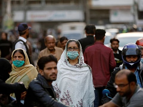 Women wear protective masks as they walk through a crowd along a market in Karachi. 