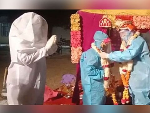 Couple ties knot in PPE kits after bride tests positive for COVID-19