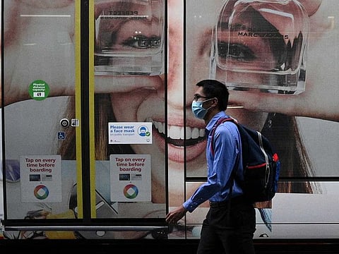 A person wearing a protective face mask walks past a tram with a public health sign asking people to wear masks following further easing of coronavirus disease (COVID-19) restrictions in Sydney, Australia, December 10, 2020. 