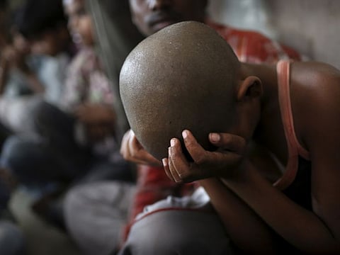 In this file picture, a young Indian bonded child labourer rests his head in his hands after being rescued during a raid by workers from Bachpan Bachao Andolan, or Save the Childhood Movement, at a garment factory in New Delhi.