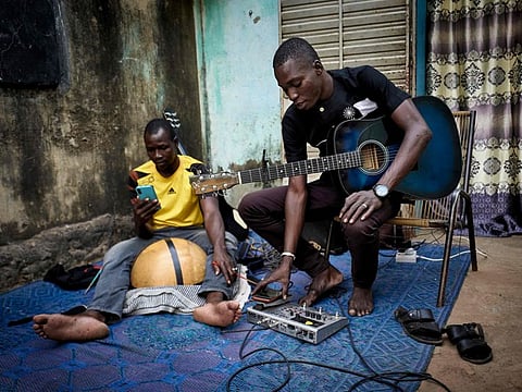 Malian musician Ali Traore (right) is seen setting his phone to record a new track in his courtyard in Bamako on October 26, 2020. 