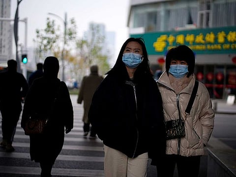 People wearing masks walk across a street, almost a year after the start of the coronavirus disease (COVID-19) outbreak, in Wuhan, Hubei province, China December 17, 2020. 
