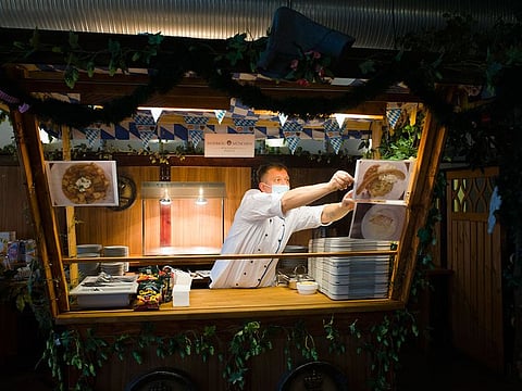 Cook Sascha Richter puts up photos of the menu at the food distribution station for the homeless people at Berlin's biggest restaurant Hofbraeu Berlin, in Berlin, Germany, Thursday, Dec. 17, 2020. 