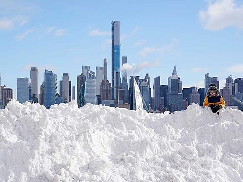 A boy plays on a mound of snow in front of the skyline of New York City in West New York, N.J., Thursday, Dec. 17, 2020. The first major snowstorm of the season left the Northeast blanketed in snow, setting records in some areas. 