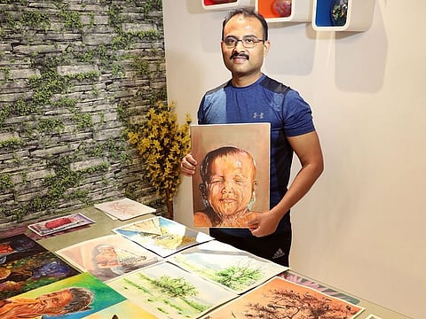 Dr Shaji Pallissery Kuzhiyil with some of his paintings.