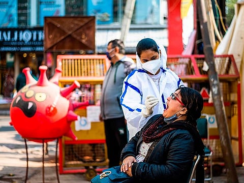 A health worker collects a swab sample from a shopper for the COVID-19 testing at a makeshift testing booth at a market area in New Delhi on December 19, 2020, as India surged past 10 million coronavirus cases.