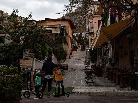 A family looks at an empty street in the Plaka district of Athens during a lockdown order by the Greek government to prevent the spread of the coronavirus in Athens, on Tuesday, April 14, 2020.