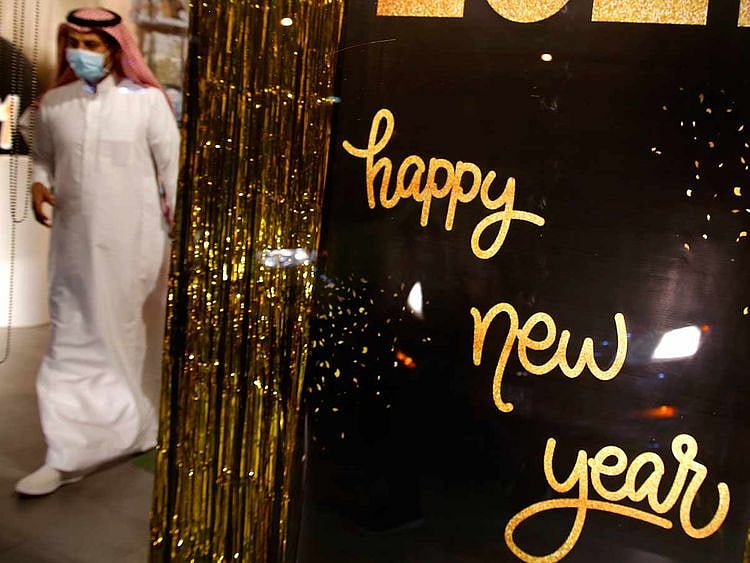 A man wearing a mask to protect from the coronavirus leaves a gift shop decorated for the New Year in Jiddah, Saudi Arabia, Friday, Dec. 25, 2020.