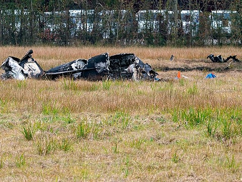 A view of the burnt wreckage of a small plane that crashed into the parking lot of a post office is shown, at left, in Lafayette, La., Saturday, Dec. 28, 2019. Several people died in the crash.