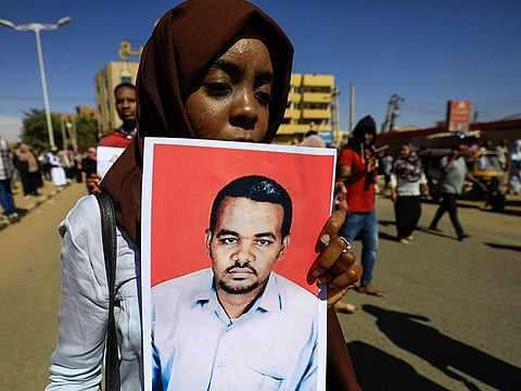  A Sudanese woman carries a portrait of the teacher Ahmed al-Khair as she celebrates after the sentencing of members of the national intelligence service to death