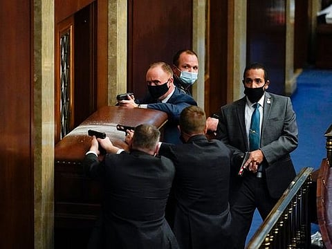 U.S. Capitol Police with guns drawn stand near a barricaded door as protesters try to break into the House Chamber at the U.S. Capitol on Wednesday, Jan. 6, 2021, in Washington.