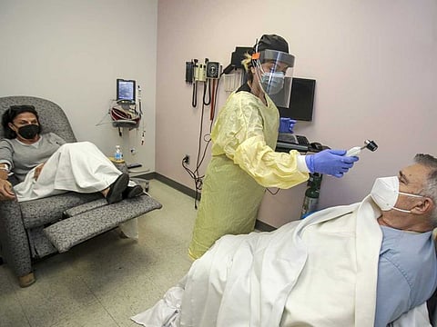 Sima Fischl-Debaroncelli, 73, a COVID-19 patient, watches as infusion coordinator Michelle Tzec checks the temperature of Dr. Peter Fischl, 72, at Desert Valley Hospital in Victorville, California, US, on December 17, 2020. Both were given Regeneron's Casirivimab and Imdevimab antibody cocktail infusion. 