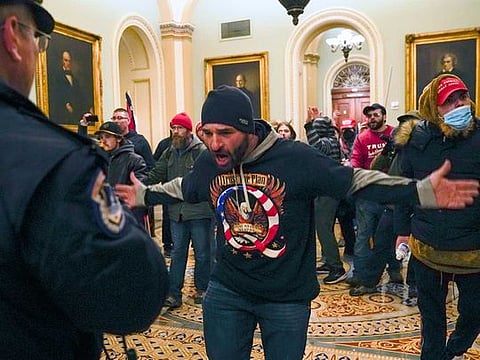 Trump supporters gesture to US Capitol Police in the hallway outside the Senate chamber after breaching the halls of the Capitol in Washington, Wednesday, Jan. 6, 2021. 