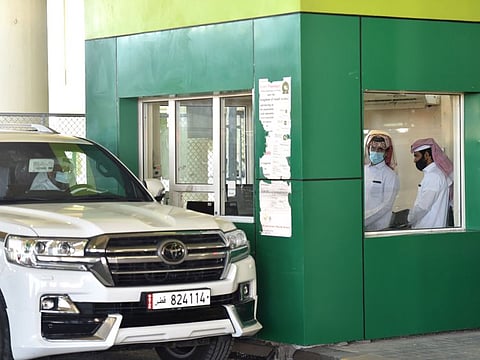 A visitor shows his documents to Saudi customs officials as he travels by car into Saudi Arabia from Qatar.