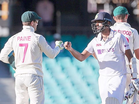 India's Ravichandran Ashwin (R) fist bumps with Australia's captain Tim Paine at the end of the third Test match at the Sydney Cricket Ground. 