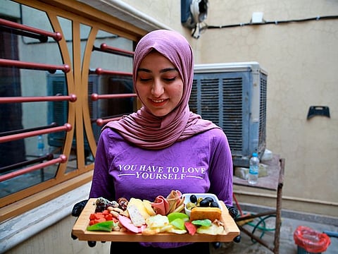 Fatima Ali shows her takeaway cheese-plate that she sells making a small but steady income, in Baghdad, Iraq, Saturday, Nov. 28, 2020. After Iraq imposed a coronavirus lockdown in March, Fatima is among a growing numbers of Iraqi women who are finding some good under the movement restrictions imposed because of the pandemic: They're starting their own businesses from home.