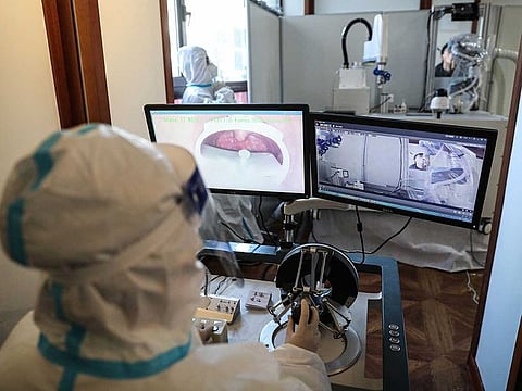 A robot machine takes a swab sample from a man to test for the COVID-19 coronavirus as a health worker monitors through the computers at a room in Shenyang, in northeastern China's Liaoning province on January 13, 2021.