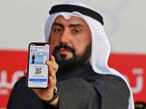 Kuwaiti Health Minister Sheikh Basel Al Sabah shows his electronic certificate to journalists after receiving the vaccine against the coronavirus, in the capital Kuwait City on January 14, 2021.