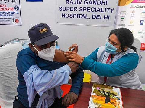 A medical worker inoculates a security staff with a COVID-19 vaccine at Rajiv Gandhi Super Speciality Hospital, in New Delhi on January 19, 2021. 