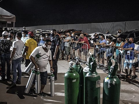 People wearing protective masks wait in line to refill oxygen tanks in Manaus. 