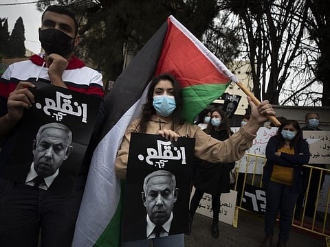 Palestinian protesters hold signs and flags during a demonstration against a visit of Israeli Prime Minister Benjamin Netanyahu to the northern Arab city of Nazareth, Israel, on January 13, 2021.  