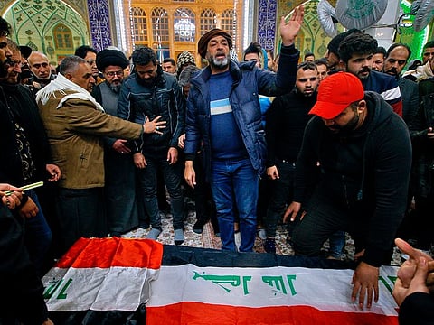 Mourners pray by the flag-draped coffin of a suicide bomb victim, Ahmed Reda, during his funeral procession at the Imam Ali shrine in Najaf, Iraq, Thursday, Jan. 21, 2021.