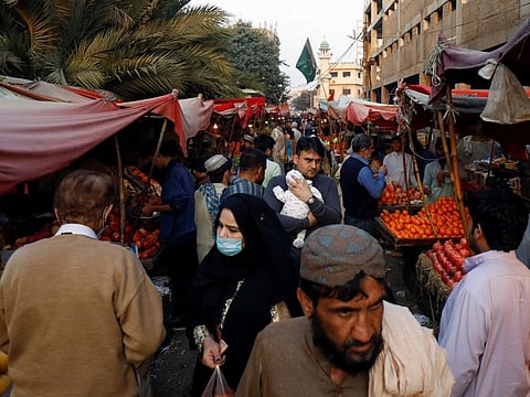 People with and without masks walk along fruit stalls at a market as the outbreak of the coronavirus disease continues, in Karachi, Pakistan January 16, 2021. 
