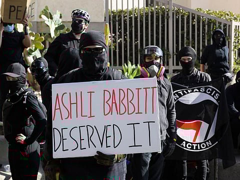 Counter-protesters hold a sign reading "Ashli Babbitt deserved it" as they await demonstrators for a "Patriot March" demonstration in support of US President Donald Trump on January 9, 2021 in the Pacific Beach neighborhood of San Diego, California. - Air Force veteran Ashli Babbitt, 35 and a fervent backer of the president from San Diego, California, was shot dead by a Capitol Police officer inside the Capitol building on January 6, 2021. 