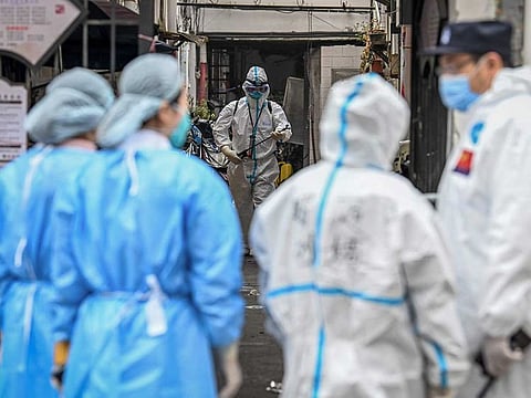 Health workers in protective gear spray disinfectant in a blocked off area in Shanghai's Huangpu district.