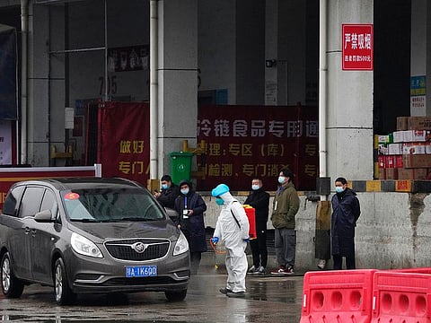 A worker in protective overall disinfects a vehicle from the World Health Organization convoy while they were visiting the Baishazhou wholesale market on the third day of field visit in Wuhan in central China's Hubei province on January 31, 2021. 