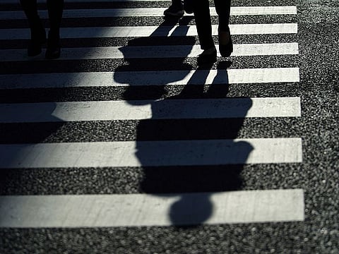 Pedestrians cast a shadow across an intersection crosswalk in Tokyo Wednesday, Feb. 3, 2021. 