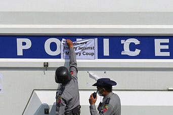 Police remove a sticker from a police vehicle during a protest against the military coup and demanding the release of elected leader Aung San Suu Kyi, in Naypyitaw, Myanmar, February 8, 2021. 