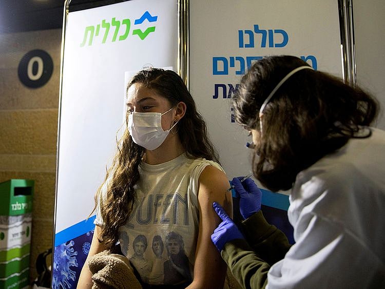 A young woman receives a vaccination against the COVID-19 at a temporary Clalit healthcare maintenance organisation (HMO) centre, at a sports arena in Jerusalem. 