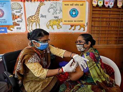 A health care worker receives a dose of COVISHIELD, a COVID-19 vaccine manufactured by Serum Institute of India, inside a classroom of school, which has been converted into a temporary vaccination centre, in Ahmedabad, India, February 9, 2021. Reuters