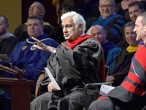 In this March 30, 2016 file photo, Ravi Zacharias, centre, speaks during the Society of World Changers induction ceremony at Indiana Wesleyan University in Marion, Ind. A law firm's investigators have released a scathing report on their four-month investigation of alleged sexual misconduct by Zacharias, who founded a global Christian ministry that bears his name.