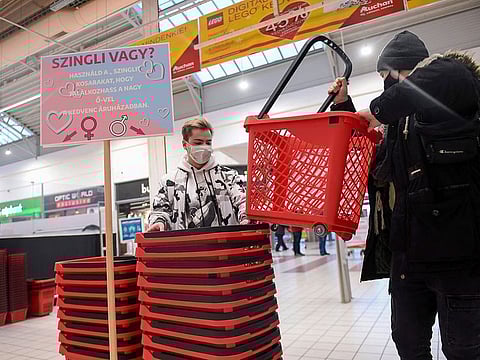 Two single young men pick up their signed plastic shopping baskets at a French Auchan supermarket in Csomor town, Hungary.